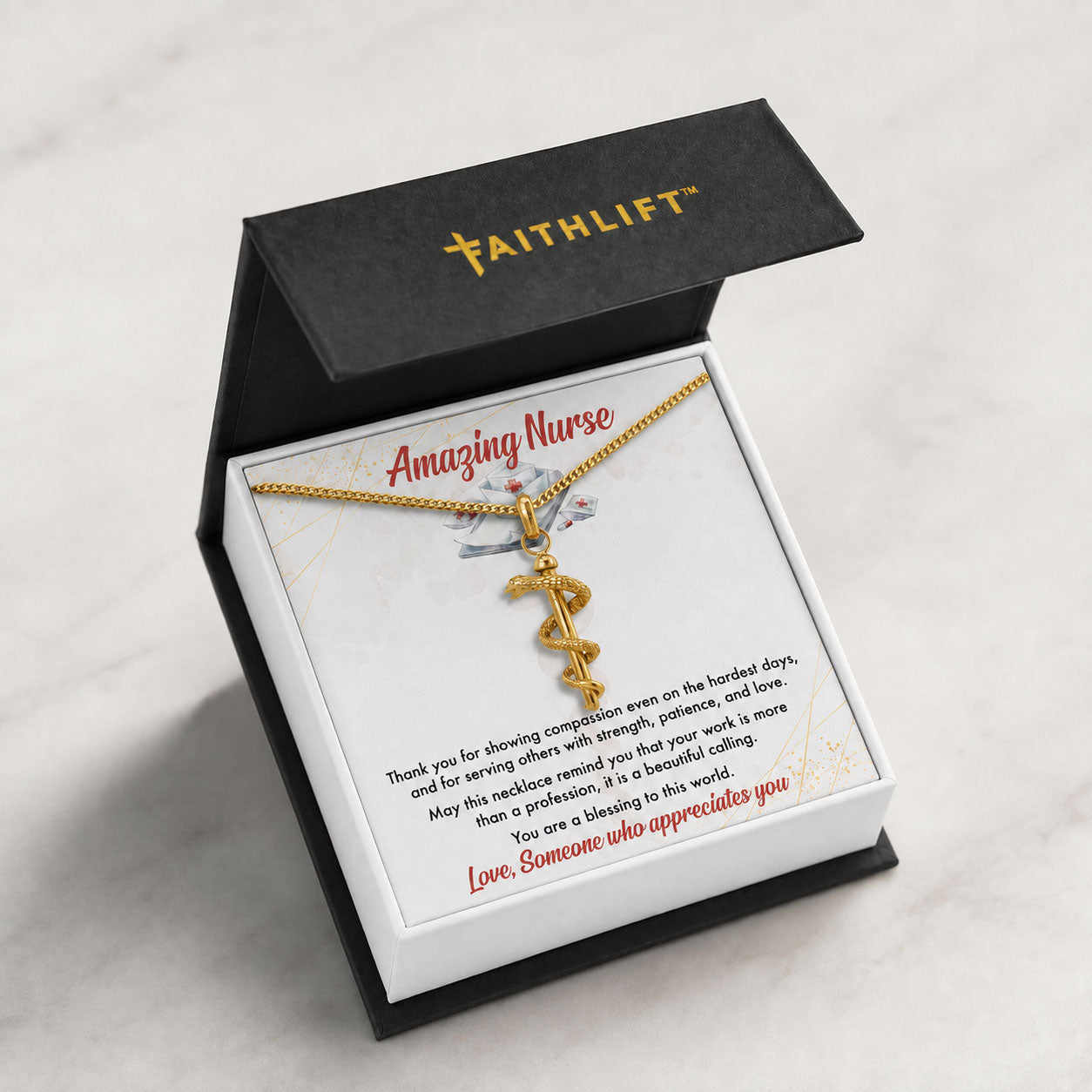 A FaithLift necklace with Rod of Asclepius Necklace displayed inside an open black gift box with a white insert card that reads 'Amazing Nurse' and a personalized message, set on a light marble surface.